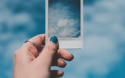 blue sky with a polaroid photo of a blue sky being held by a woman's hand wearing blue nail varnish