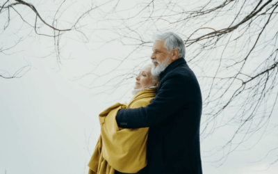 white older couple embracing each other with a grey sky in the background