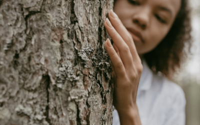 woman by a tree with her hand touching the bark