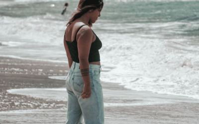 young woman wearing jeans on the beach looking down to the water