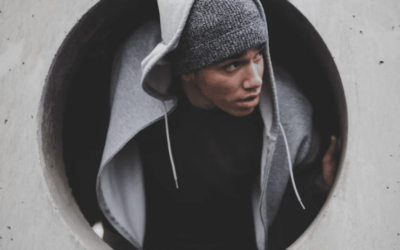 young man wearing a hoodie poking his head out of a circular opening