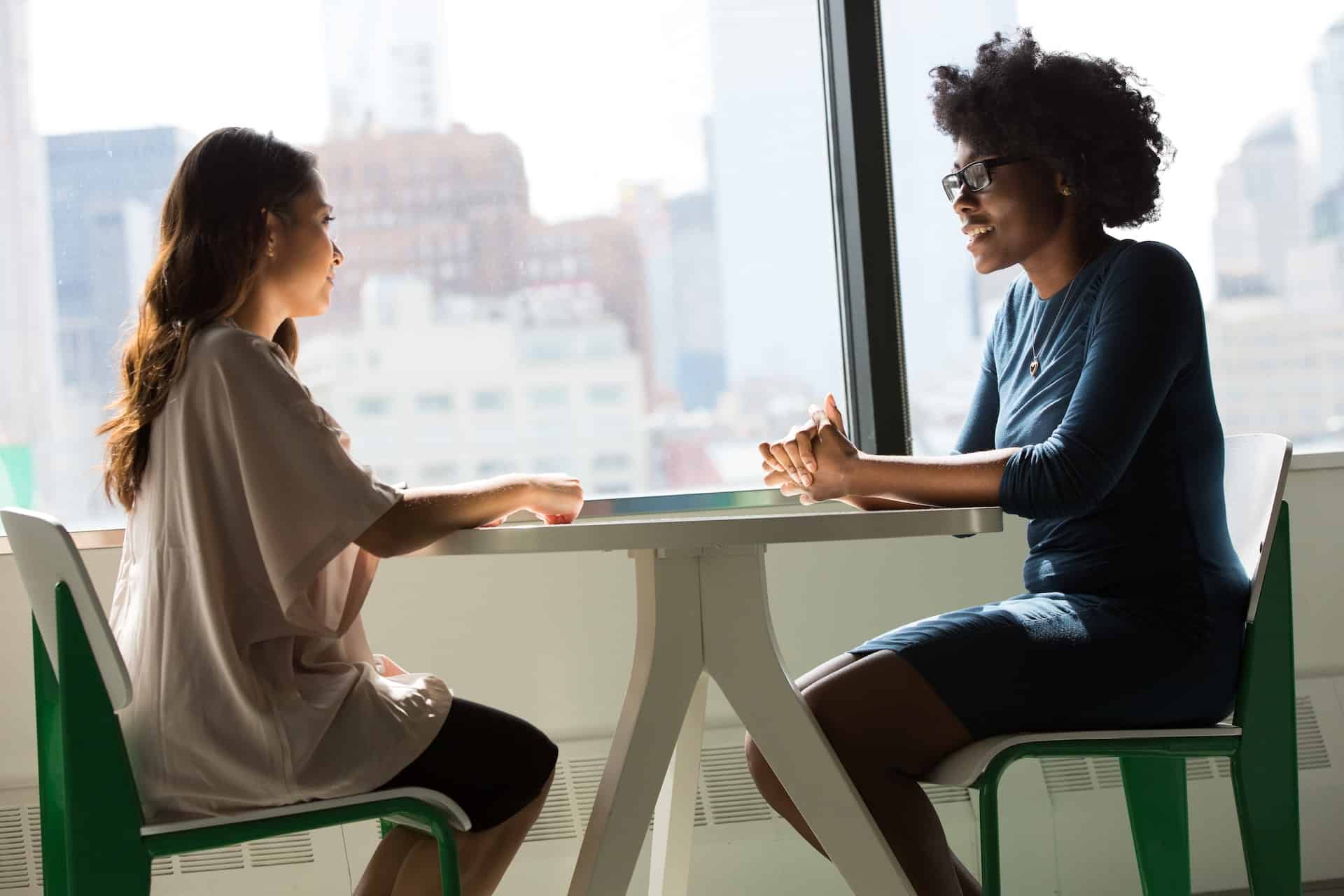 Two women talking at a table in the office