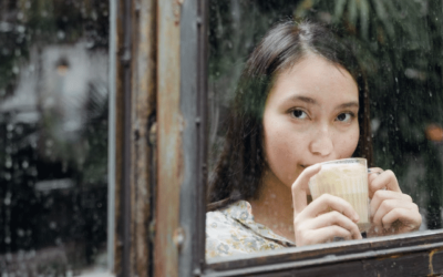 asian woman sipping a hot drink by a window
