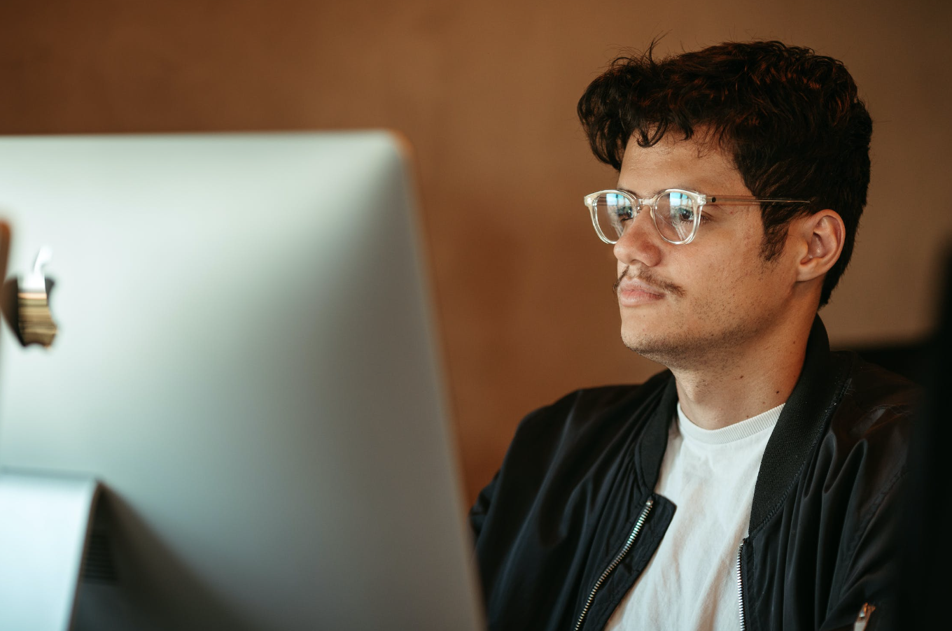 man wearing glasses looking at a mac desktop
