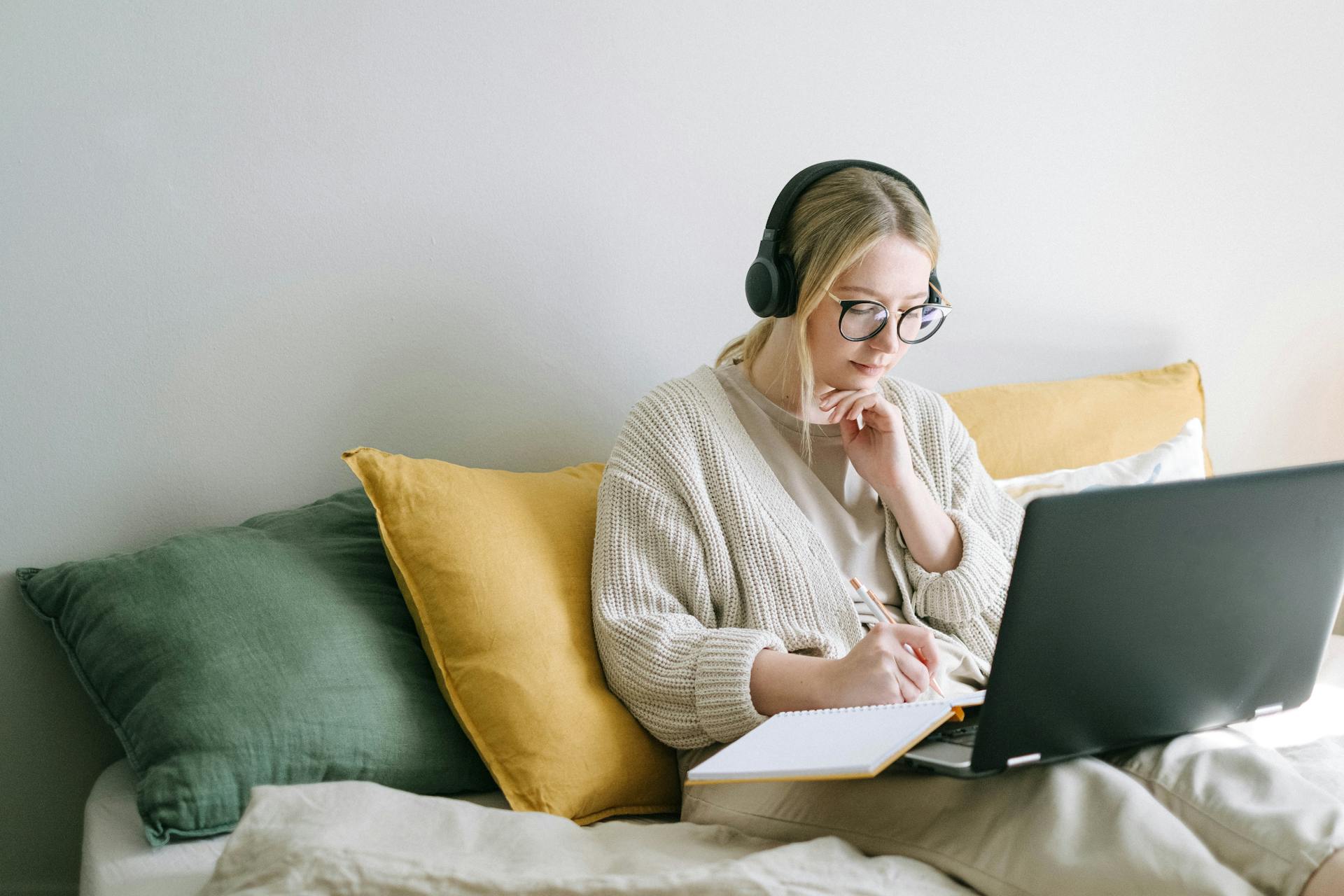 Woman sitting on her laptop on her bed.