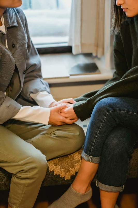 Two people holding hands and engaging in eating disorder therapy to show comfort for a blog answering difficult questions like 'do i have anorexia?'