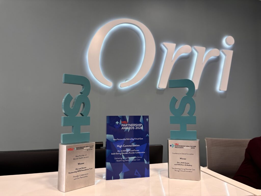 IMG_6873 | Orri Several award plaques stand upright on a white table, including a blue'HSJ Partnership Awards 2026' centerpiece, with teal decorative symbols in the background.